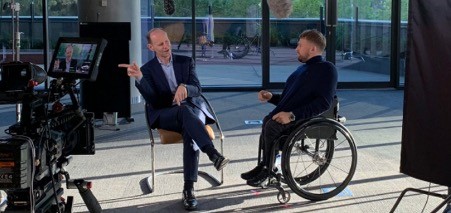 ANZ CEO Shayne Elliott and ANZ Ambassador Dylan Alcott OAM sit in a room with video cameras talking to each other and smiling. 