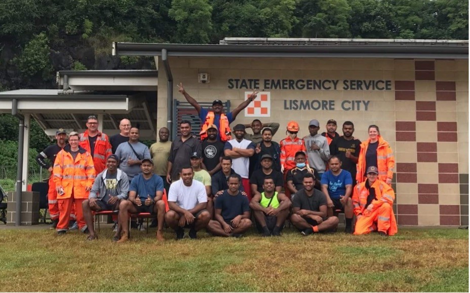 A group of Fijian workers stand with local state emergency services in Lismore